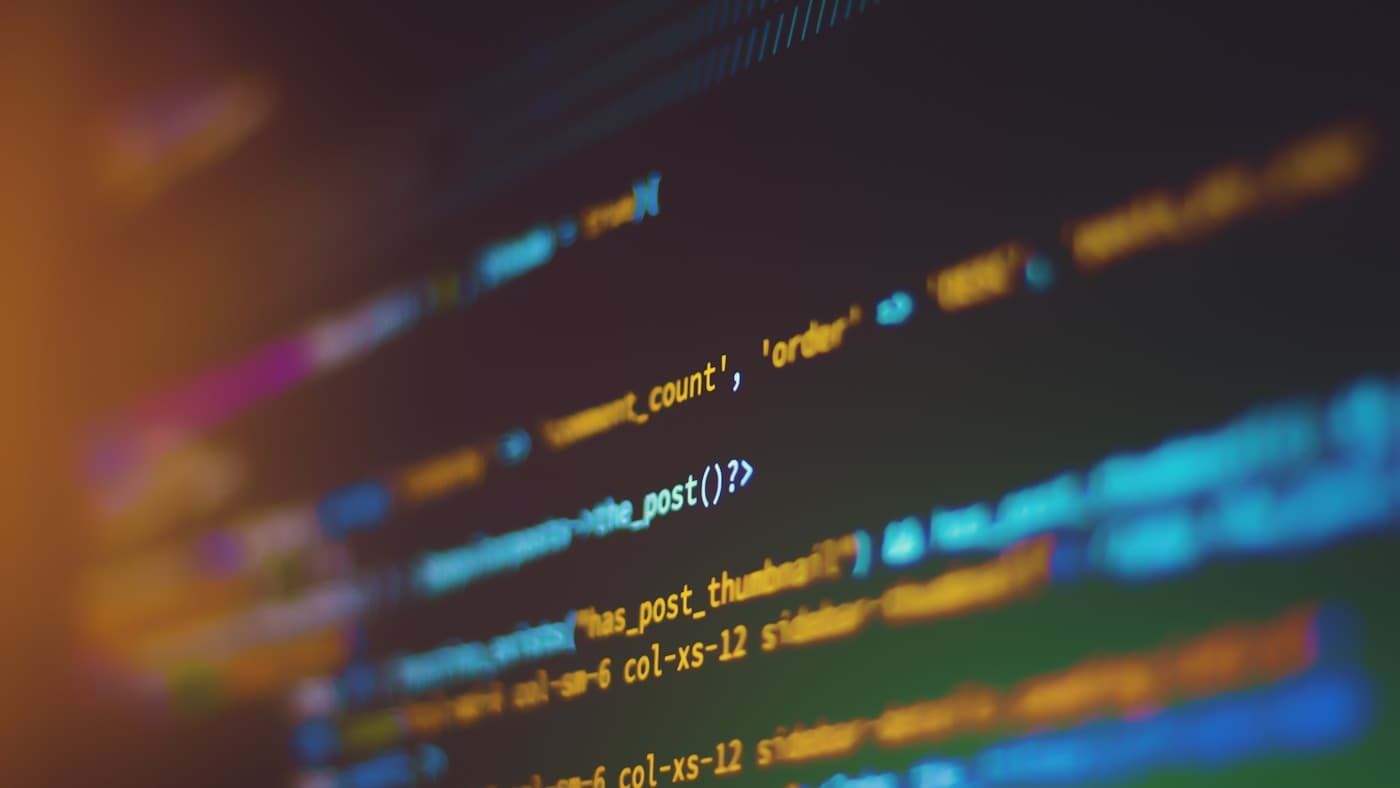 Cinematic bokeh shot of code on a screen in a dark room — the solo developer's command centre where nineteen AI agents run