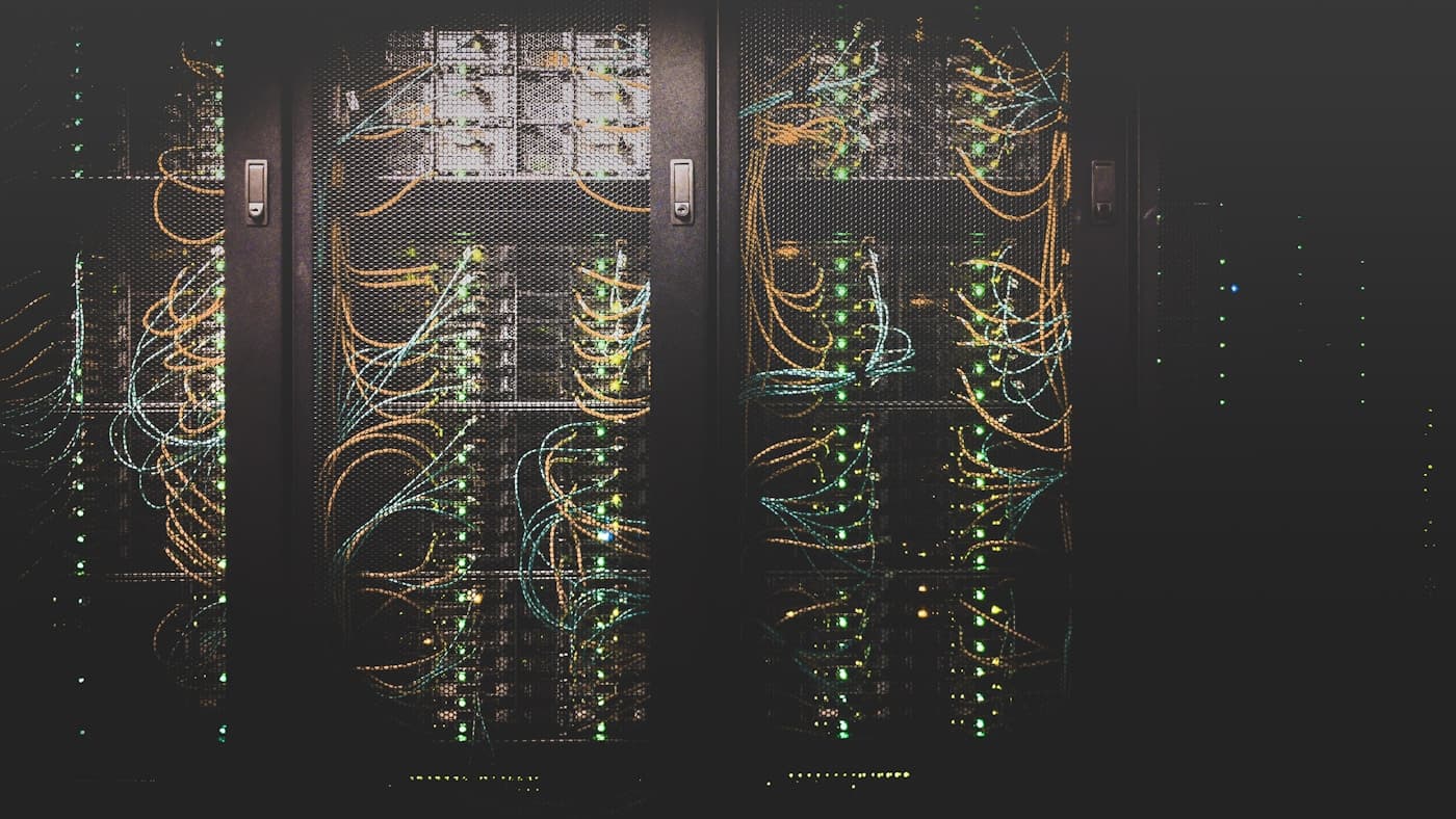 Multiple monitors showing code in a dark developer workspace with warm red ambient lighting