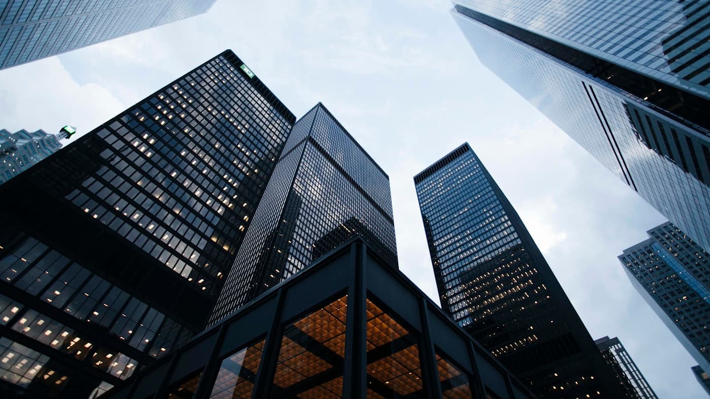 Modern glass architecture reflecting the sky — the kind of layered foundation the CX industry is missing